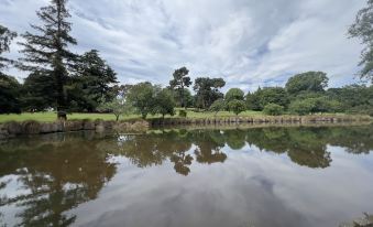 a serene landscape with trees and a body of water , reflecting the sky and clouds in the water at Cedar Lodge Motel