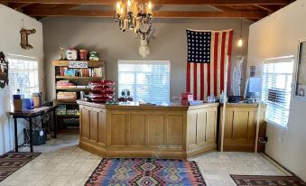 a well - decorated office with wooden furniture , a chandelier , and an american flag hanging from the ceiling at Antelope Lodge