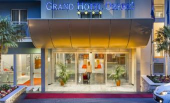 the entrance of a grand hotel with a red carpet and large windows , illuminated by lights at Aminess Grand Azur Hotel