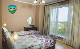 a bedroom with a bed , nightstand , and large window overlooking a beautiful view of the countryside at Holiday Village