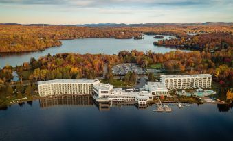 aerial view of a large hotel surrounded by trees and a lake , with mountains in the background at Estérel Resort