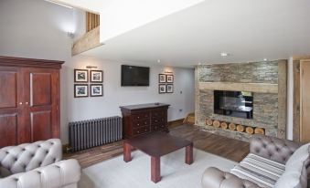 a living room with a stone fireplace , a flat - screen tv mounted on the wall , and a comfortable couch at The New Inn