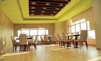 a large room with wooden floors and tables , chairs , and a yellow ceiling , filled with tables and chairs arranged in rows at Royal View Hotel