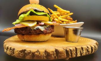 a hamburger and fries are served on a wooden platter with a small cup of sauce at Inn at the Falls