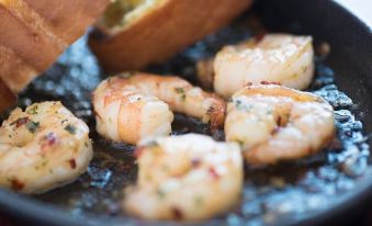a black frying pan filled with various seafood , including shrimp and scallops , being cooked in a sauce at The Olde Peculiar