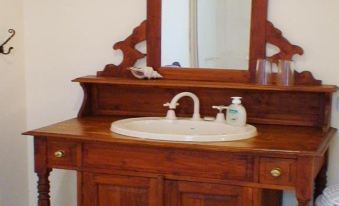 a wooden sink cabinet with a mirror above it , and a white towel hanging on the wall at Albury Cottages