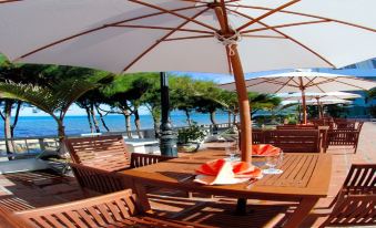 a wooden dining table with chairs and an umbrella is set up on a patio overlooking the ocean at Seagull Hotel