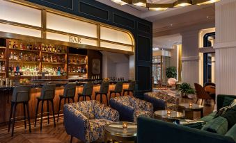 a modern bar with a black bar counter , blue chairs , and wooden floors , as well as various seating options such as couches and chairs at Canopy by Hilton Philadelphia Center City