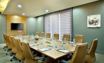 a conference room with a long table , chairs , and water bottles set up for a meeting at Hilton Garden Inn Tabuk