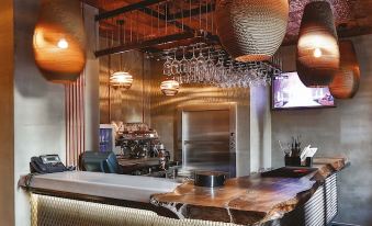 a modern bar with a wooden counter , large windows , and hanging lights , as well as a tv screen on the wall at Hotel the Public - Special Category