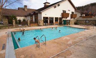 a group of people are enjoying a large swimming pool and surrounding facilities in a rural setting at The Inn at Holiday Valley