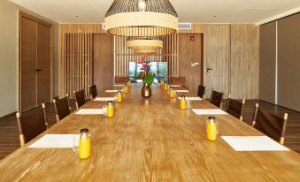 a long wooden dining table with chairs arranged around it , ready for a group of people to sit and eat at Island Escape Burasari