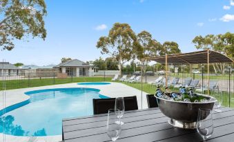 a backyard with a pool , dining table , and chairs , as well as umbrellas and lounge chairs at Sanctuary Inn on Westernport