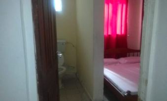 a room with a bed , window , and curtain , as well as a doorway leading to another room at Eddys Resort