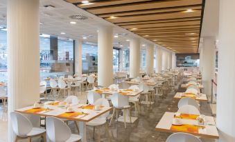 a large dining room filled with white chairs and tables , ready for guests to enjoy a meal at Hotel Dos Playas