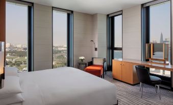 a modern hotel room with a large window offering a view of the city , a bed , and a chair at Park Hyatt Doha
