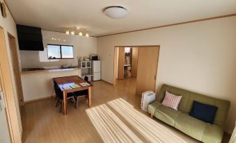 a spacious living room with hardwood floors , a green couch , and a dining table in the background at Cottage Sunset-Village