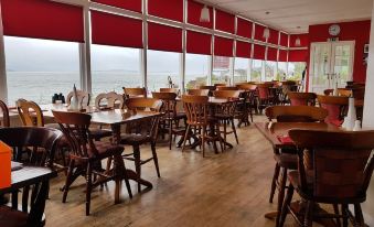 a dining room with wooden chairs and tables , along with a view of the ocean through large windows at The Osborne