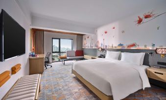The bedroom is furnished with a bed, desk, and large windows at Hilton Garden Inn Guangzhou Tianhe