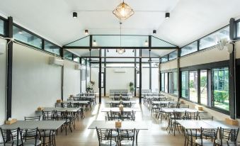 a large , open room with wooden floors and white walls has several tables and chairs arranged for a group of people at Pimtara Beach Resort