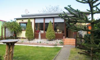 a small , yellow house surrounded by a lush green garden , with trees and bushes in the yard at Karli