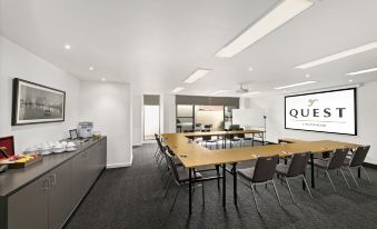 "a conference room with a long table and chairs , a large screen displaying the word "" quotidien "" on the wall , and a" at Quest Cheltenham