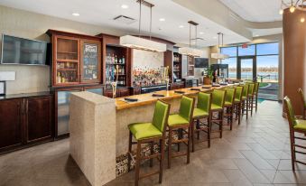 a modern restaurant with a bar area , where several people are seated and enjoying their meals at Holiday Inn Owensboro Riverfront
