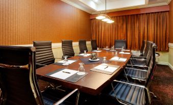 a conference room with a wooden table surrounded by chairs , and several wine glasses placed on the table at Holiday Inn Long Island - Islip Arpt East