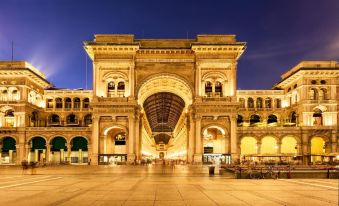 a large , ornate building with a balcony and arches is illuminated at night in an urban setting at Hotel Forum