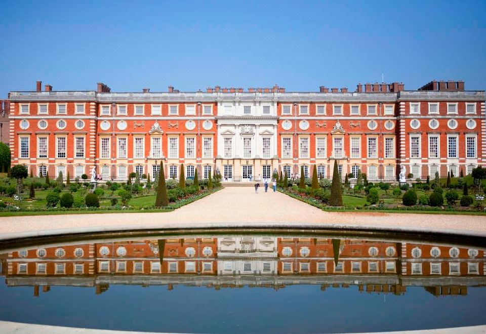 a large , ornate building with a red roof and white walls is reflected in the water below at London Twickenham Stadium Hotel, a Member of Radisson Individuals