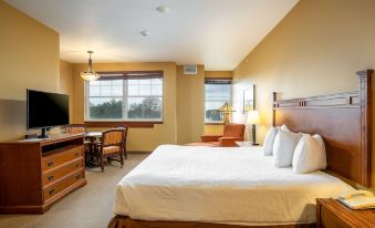 a hotel room with a large bed , a desk , a chair , and a window overlooking the city at Honey Creek Resort