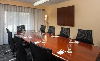 a conference room with a large wooden table , several black chairs , and a whiteboard on the wall at Courtyard Chicago Wood Dale / Itasca