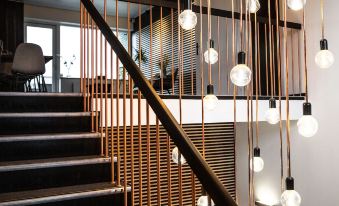 a staircase with a black railing and wooden steps is illuminated by hanging light bulbs at Hotel-B