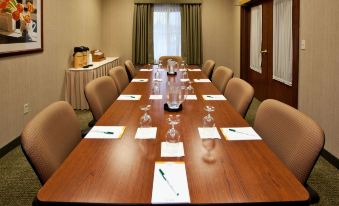 a conference room set up for a meeting , with a wooden table and chairs arranged in a rectangular formation at La Quinta Inn & Suites by Wyndham Bannockburn-Deerfield