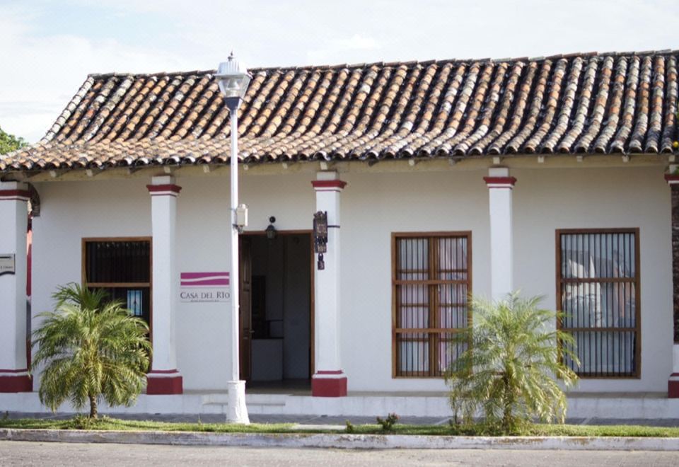 "a white building with red trim and a sign reading "" pelastro "" is shown in front of a street lamp" at Casa del Rio