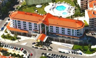 an aerial view of a large hotel with a pool and tennis court , surrounded by other buildings and parking lots at Riviera Hotel