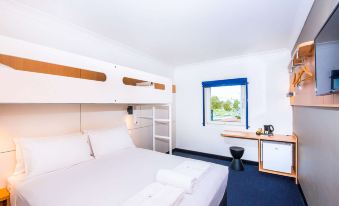 a room with a double bed and bunk beds , as well as a desk and chair at ibis budget Casula Liverpool