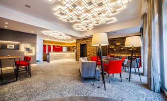 a modern hotel lobby with red and gray furniture , large light fixtures , and a marble floor at Hotel am Dom