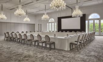 a large , elegant conference room with multiple rows of chairs arranged in a symmetrical pattern , and a projector screen mounted on the wall at Rosewood Miramar Beach