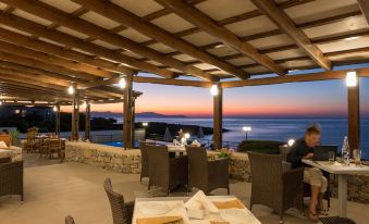 a dining area with a view of the ocean , surrounded by tables and chairs , creating a pleasant atmosphere at Lena Beach Hotel
