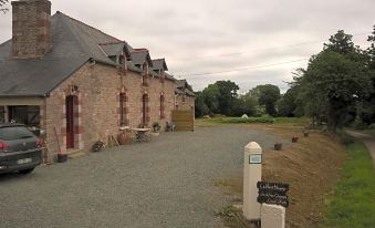 a large brick building with multiple windows and a sign in front of it , surrounded by a gravel driveway at La Clef des Champs