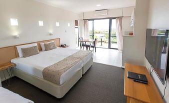 a large , well - made bed with a wooden headboard is in the middle of a hotel room at Margarets Beach Resort