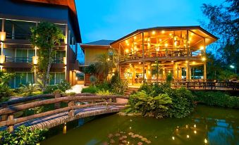 a beautiful house with a pond in front of it , surrounded by lush greenery and trees at Blues River Resort