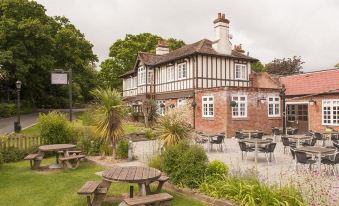 a large brick building with a chimney , surrounded by trees and a grassy yard with picnic tables at The Fishbourne