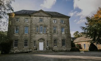 a large stone building with multiple windows and doors , situated in front of a clear sky at Roundwood House