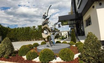 a statue of a person holding a sword in front of a building with bushes and bushes in front at Hotel Mirror Skopje