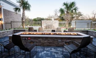 a patio area with a fire pit surrounded by chairs and tables , creating an inviting atmosphere at Courtyard Lake Jackson