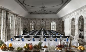 a long dining room with multiple tables set up for a formal event , complete with wine glasses , plates , and utensils at Finca Cortesin Hotel Golf & Spa