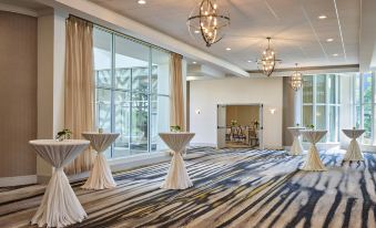 a hotel ballroom with two cocktail tables set up for a formal event , surrounded by chairs and chandeliers at Delta Hotels Chicago Willowbrook