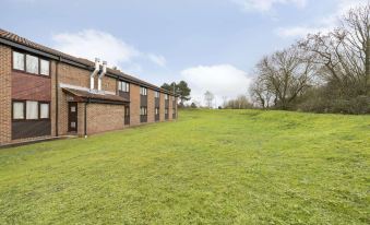 a grassy field with several buildings , possibly a hotel or motel , located on the side of a hill at Days Inn by Wyndham Sedgemoor M5